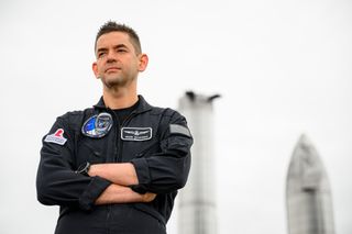 Jared Isaacman standing in front of spaceship prototypes