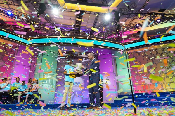 Bruhat Soma, 12, of Tampa, Fla., accepts the trophy from EW Scripps Company Chairman and CEO Adam Symson after winning the Scripps National Spelling Bee in Oxon Hill, Md., Thursday May 30, 2024. (AP Photo/Jacquelyn Martin)