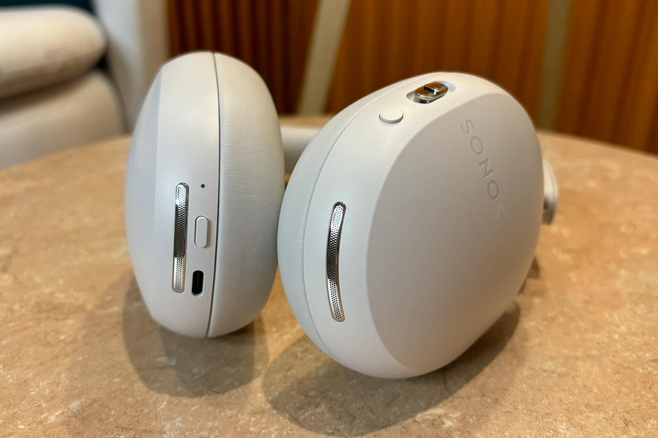 White headset lying flat on a small table, showing the buttons on both sides. 