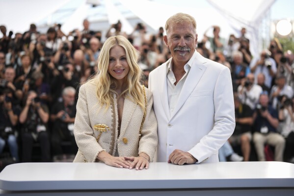 Sienna Miller, left, and Kevin Costner pose for photographers during the photo call for the film 