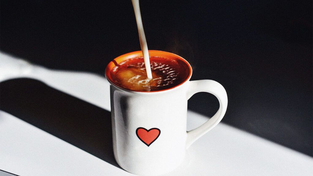 white cup with red heart pattern containing black tea