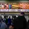 Customers line up at a Costco food court, advertising a hot dog and soda special for $1.50.