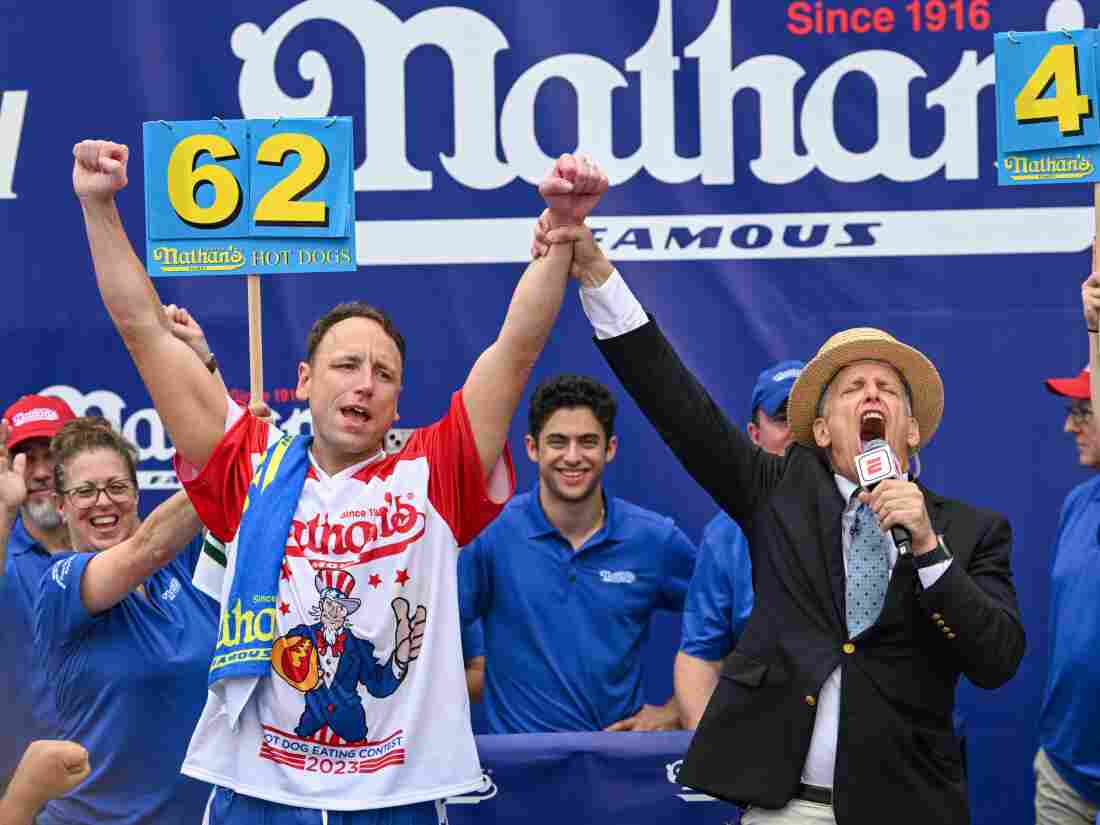 Chestnut raises his arms in victory, holding the emcee's hand, on stage at Coney Island.