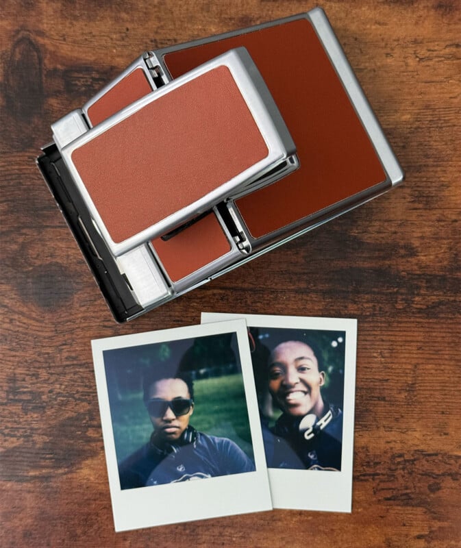 A vintage Polaroid camera with a brown and silver design on a wooden surface, accompanied by two instant photos.  The photos show two smiling individuals, each wearing sunglasses and headphones.