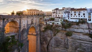 The arch of the bridge glowed in warm colors with white buildings in the distance.