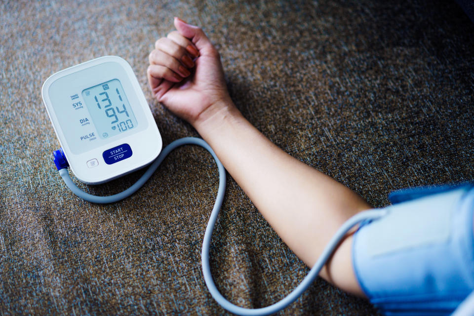 Close-up of a person's arm with a blood pressure cuff, showing the reading of 131/94 mmHg and a pulse rate of 100 on the monitor