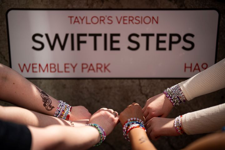 Taylor Swift fans pose with their bracelets in front of the 