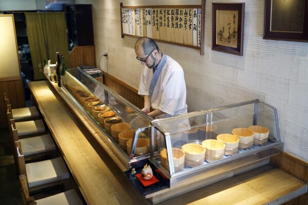 Yosuke Miura prepares a rice ball with pieces of grilled salmon at Onigiri Asakusa Yadoroku, Tokyo's oldest onigiri restaurant, on June 3, 2024, in Tokyo.  Word 