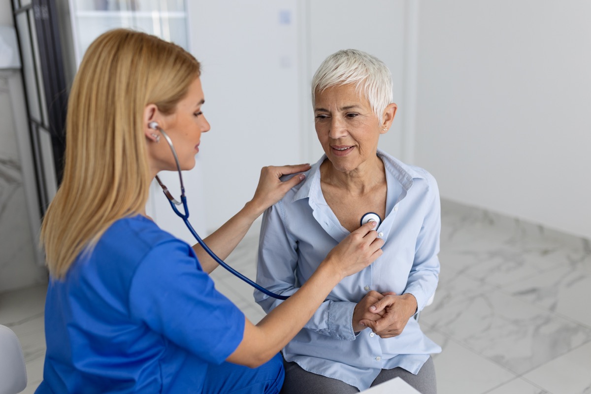 A caring female doctor uses a phonendoscope to examine the heartbeat of an elderly patient during a hospital consultation. A nurse or general practitioner uses a stethoscope to listen to a woman's heartbeat at the clinic.