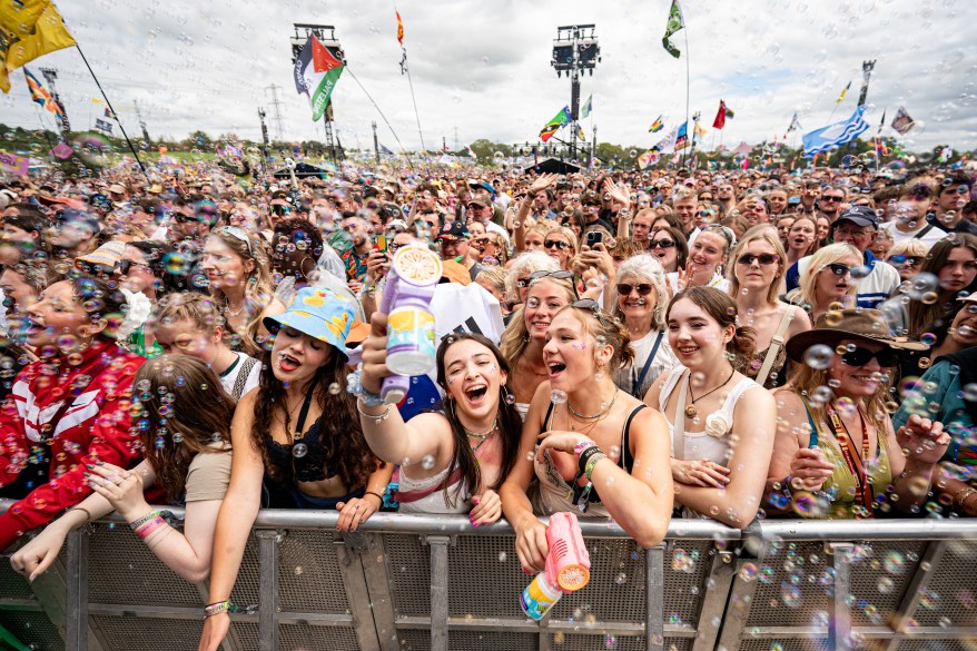 Music fans blow bubbles while watching festival performers on the Pyramid Stage.