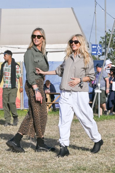 Sienna Miller arrives at the Glastonbury Festival, in Barbour, standing in a field with another woman on June 28, 2024.