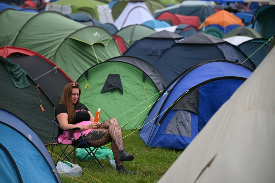 A festival goer sits near the tents on day three of the Glastonbury Festival at Worthy Farm, Somerset, England