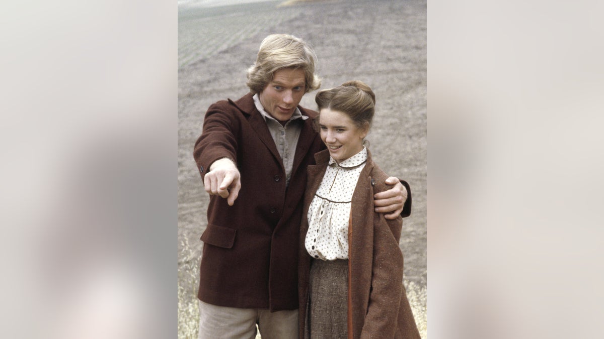 Dean Butler shows something as Melissa Gilbert looks on.