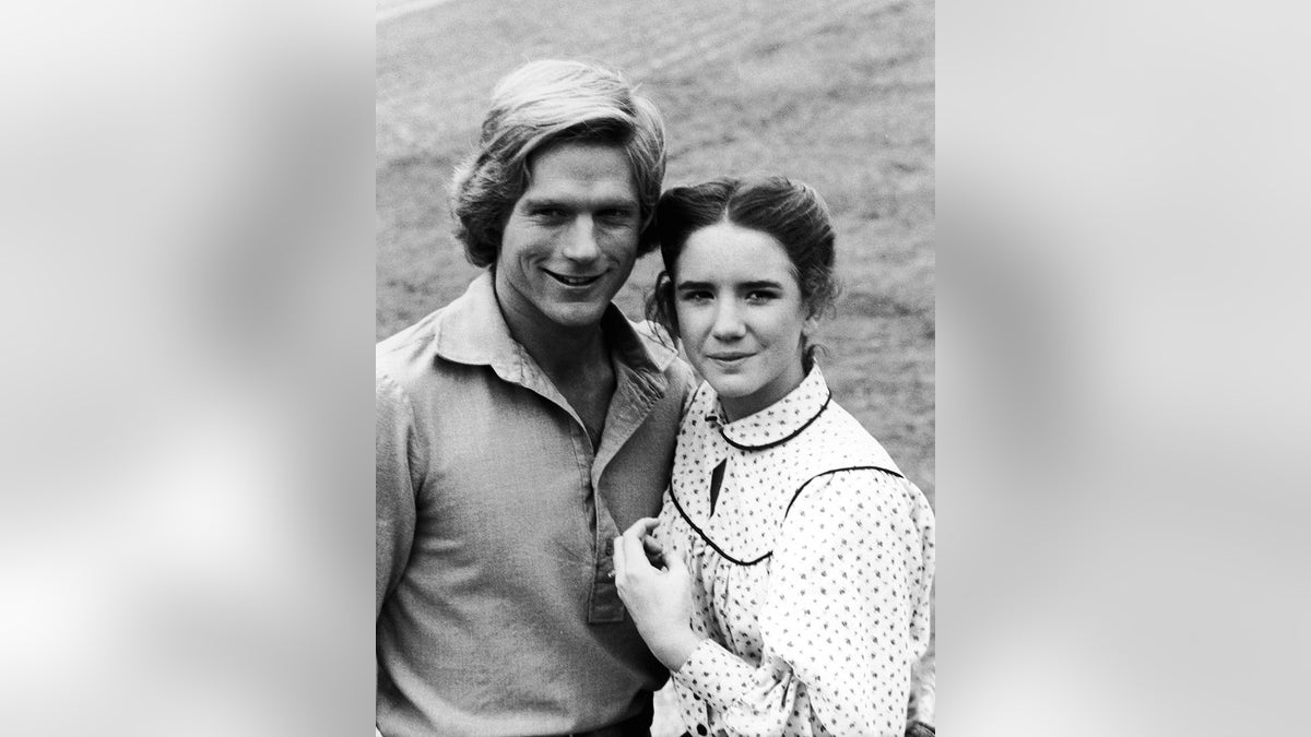 Dean Butler smiling next to Melissa Gilbert in a black and white polka dot dress.