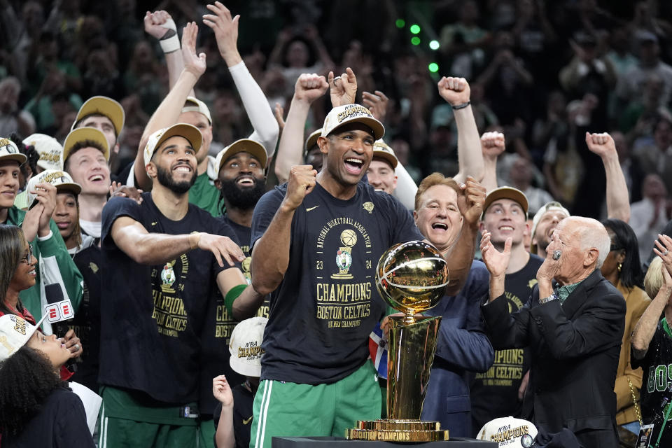 Boston Celtics center Al Horford, center, and forward Jayson Tatum, center left, celebrate with teammates near the Larry O'Brien championship trophy after winning the NBA championship with a victory in Game 5 against the Dallas Mavericks on Monday June 17, 2024, in Boston.  (AP Photo/Charles Krupa)