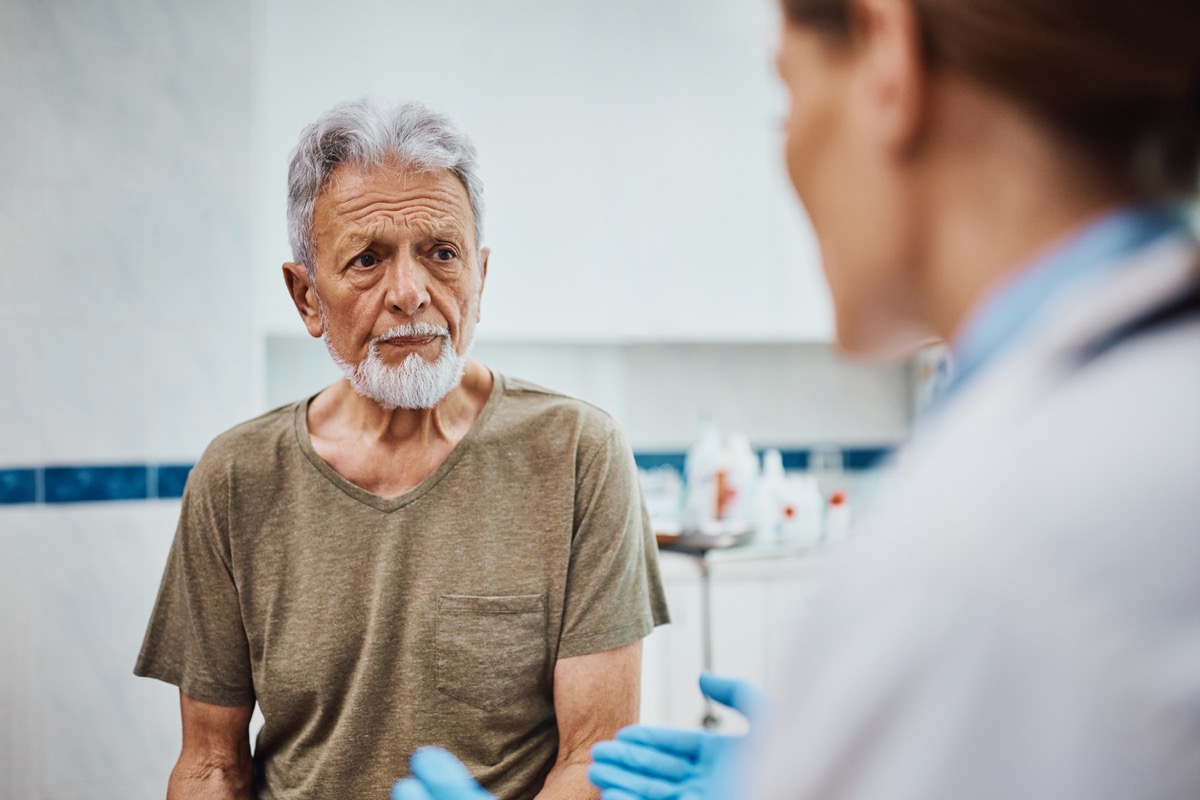 Concerned elderly patient listening to his doctor after a medical examination at the clinic.