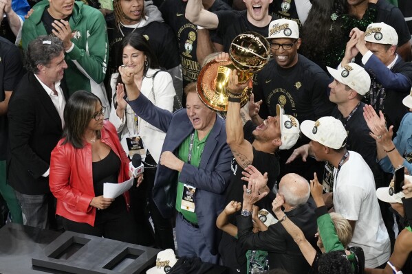 Boston Celtics head coach JJoe Mazzulla, center right, raises the trophy alongside owner Stephen Pagliuca, center left, after defeating the Dallas Mavericks in Game 5 of the NBA Basketball Finals , Monday, June 17, 2024, in Boston.  (AP Photo/Michael Dwyer)