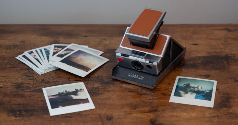 A vintage Polaroid Land camera sits on a wooden surface.  On the left is a series of Polaroid photos and two additional photos in the foreground.  The images show landscapes and a dog.  The scene is warm and nostalgic.