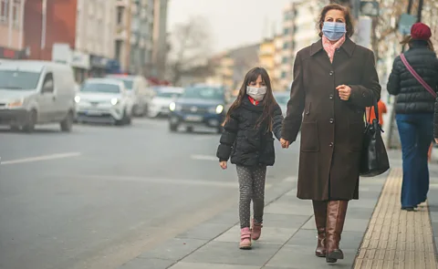 A mother and her daughter both wear masks to protect themselves from air pollution