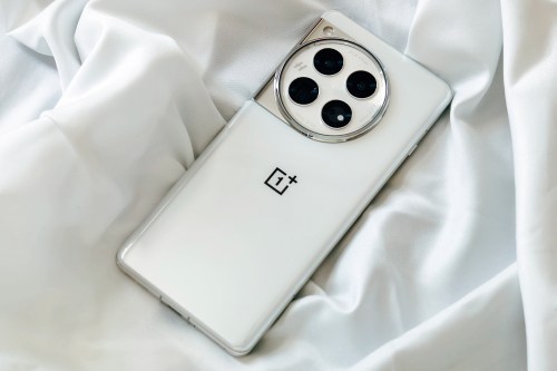 OnePlus 12 Glacial White on a crinkled satin white fabric.