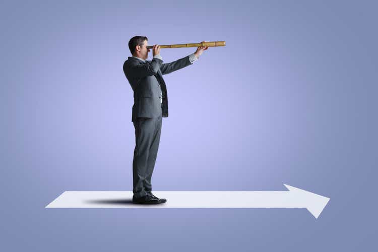 Man standing on top of a spire looking through a spyglass