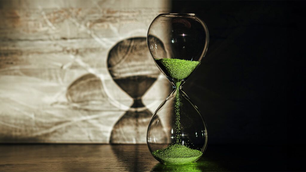 Hourglass with green sand and shadow