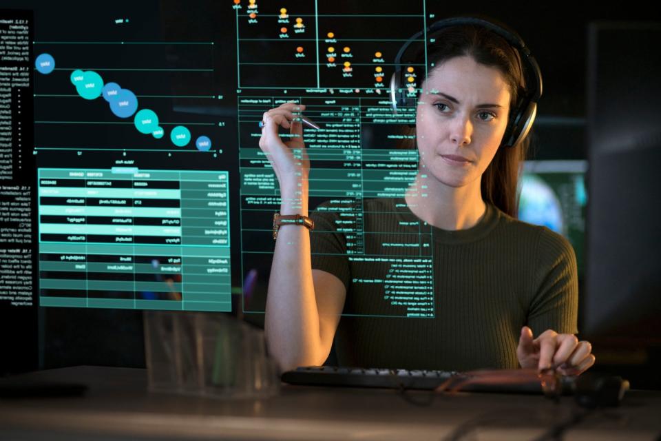 Person looking at graphs and data on transparent computer screen.