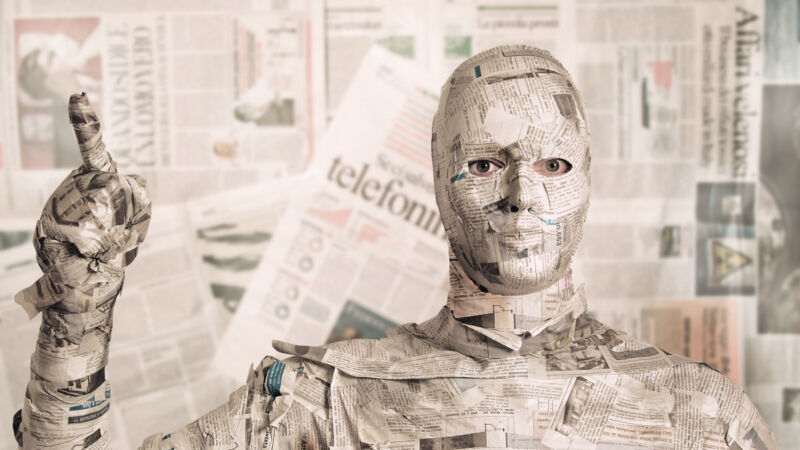 A man covered in newspapers.