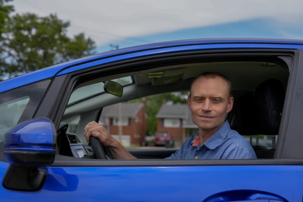 Caleb Jud, 33, poses for a portrait in his Honda Fit, Monday, May 13, 2024, in Cincinnati.  (Many Americans still aren't sold on the idea of ​​going electric for their next car purchase. High prices and a lack of easy-to-find charging stations are major sticking points, new survey finds . Jud said he was considering an electric vehicle, but might end up buying an electric car with a plug-in hybrid – if he goes electric.