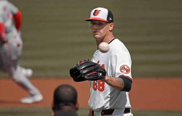 March 31, 2024: Orioles starter Tyler Wells, right, receives a new game ball from umpire Ramon DeJesus after giving up a 2-run homer to the Angels' Taylor Ward, left, in the first inning.  The Orioles lost to the Angels 4-1 at Oriole Park at Camden Yards.  (Kenneth K. Lam/Staff)