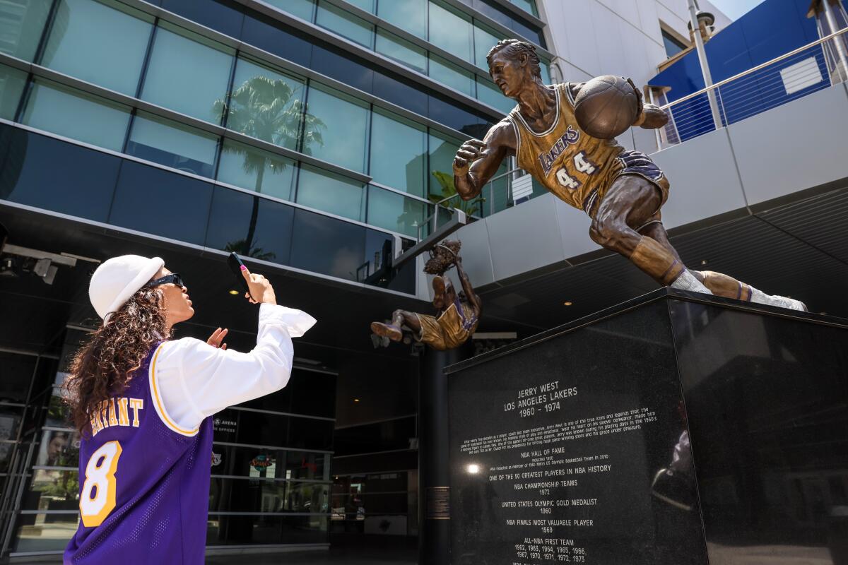 Sankara XT stops to photograph a statue of Jerry West at the Crypto.Com Arena after hearing the news of his death on Wednesday.