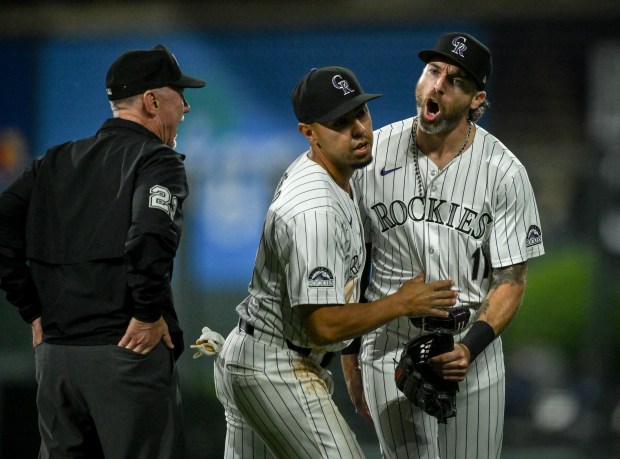 Alan Trejo (13) holds off the Colorado Rockies' Jake Cave (11) as he chats with umpire Lance Barksdale (23) after the Los Angeles Dodgers scored seven runs early in the evening's 11- 9 of the Dodgers at Coors Field in Denver on Tuesday, June 18, 2024. (Photo by AAron Ontiveroz/The Denver Post)