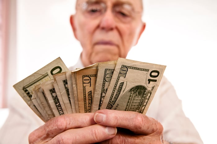 A person counting a stack of assorted banknotes in their hands.