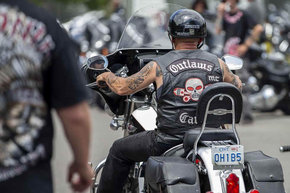 a motorcyclist wearing a leather jacket with a skull and pistons logo