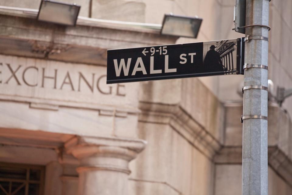 Wall St street sign in front of a stone building with Exchange engraved on the door.