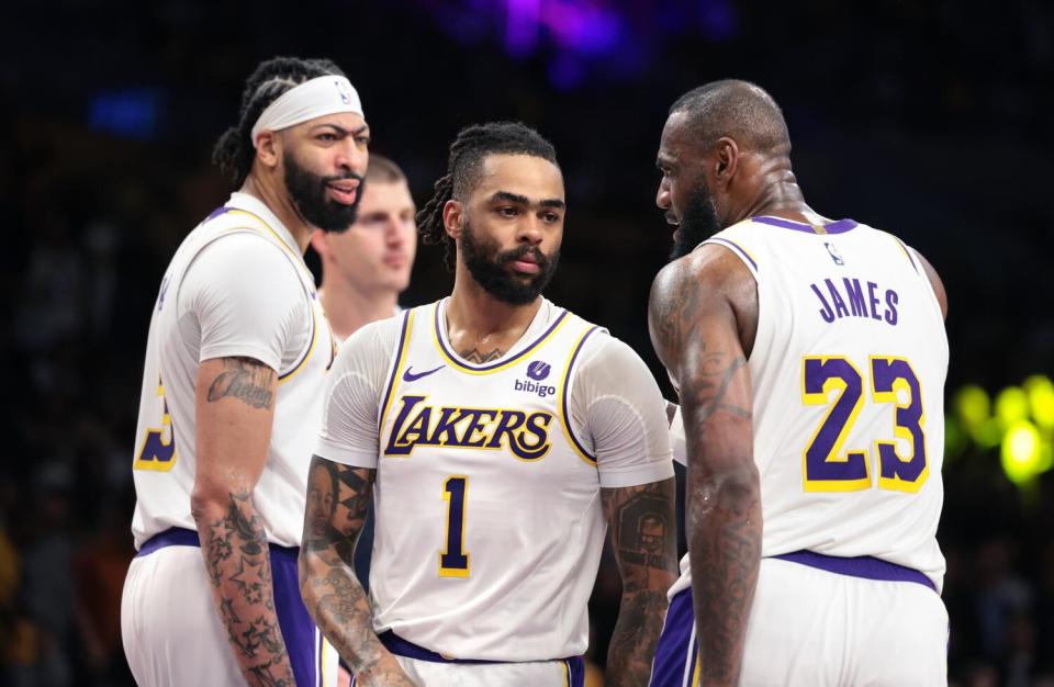 Lakers' LeBron James chats with D'Angelo Russell while Anthony Davis frowns as he looks down the court.