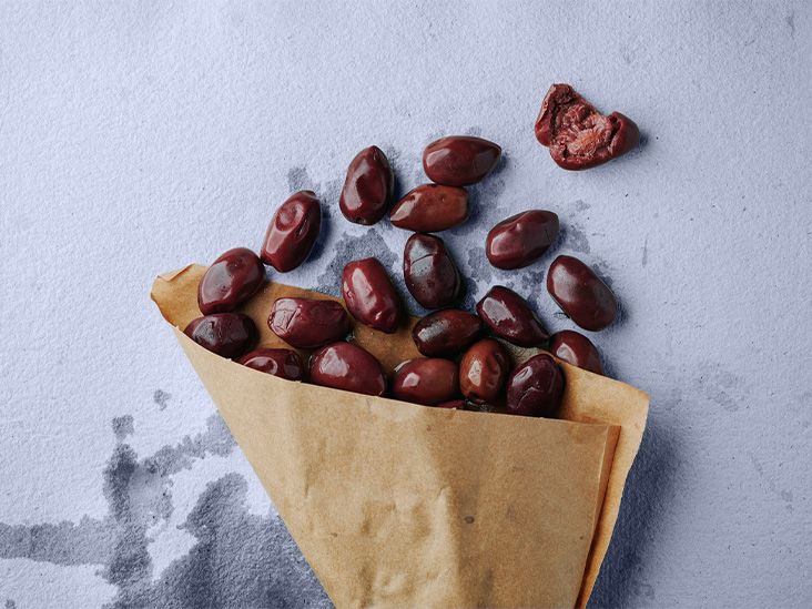 Black olives in a paper bag on a flat surface