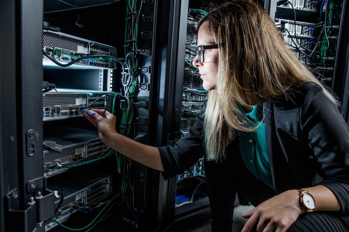 An engineer checks wires and switches on a server tower in a data center.