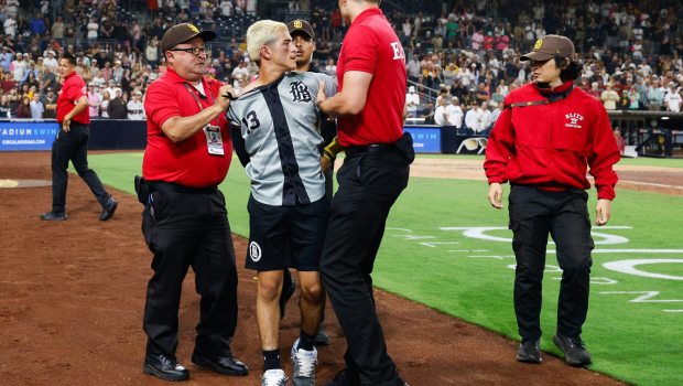 A fan is restrained by security after running onto the field during the Padres' postgame celebration. (Meg McLaughlin/The San Diego Union-Tribune)