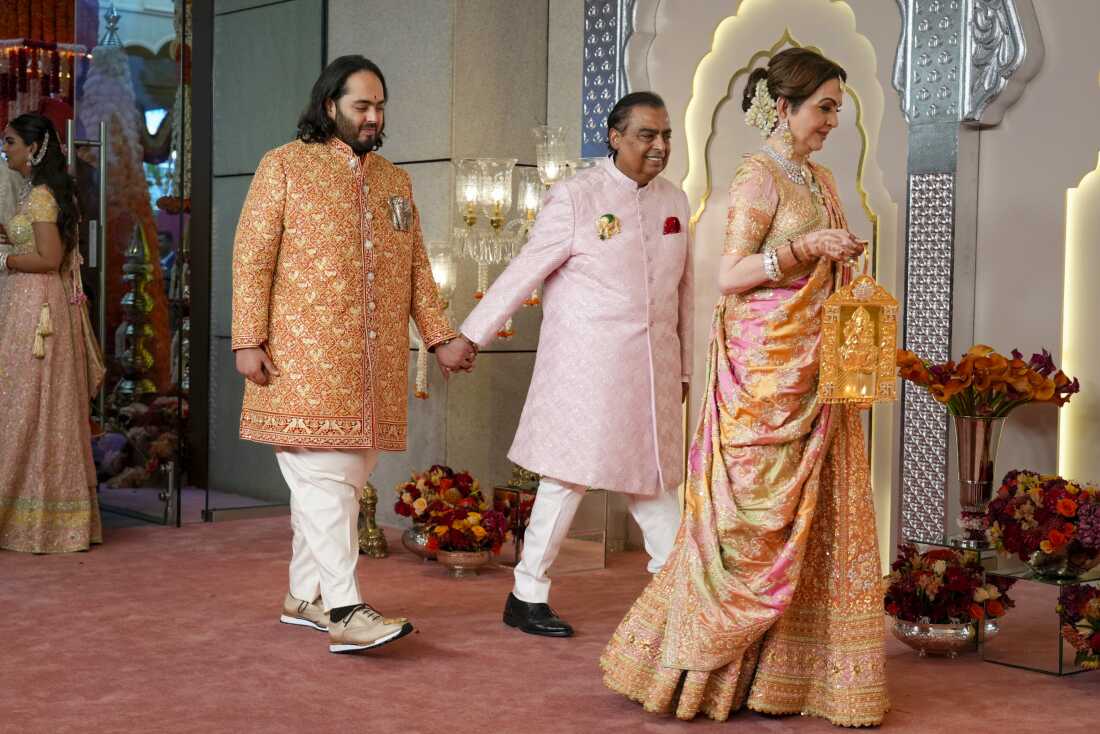 Billionaire Mukesh Ambani, center, takes his son Anant Ambani by the hand as they walk with Nita Ambani, right, during the wedding of Anant and Radhika Merchant at the Jio World Convention Centre in Mumbai, India, Friday, July 12, 2024. (AP Photo /Rajanish Kakade)