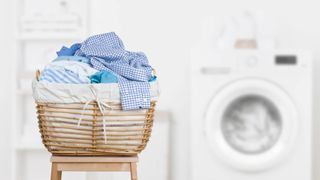 A basket full of dirty laundry in front of a washing machine