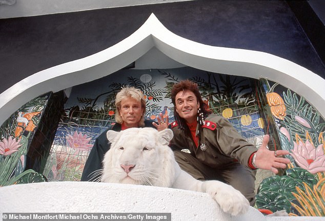 Magicians Siegfried and Roy pose for a portrait with a white tiger in their enclosure at the Mirage Hotel in March 1990