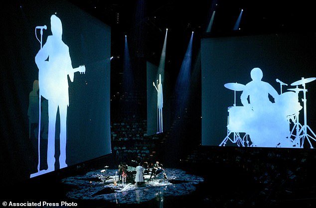 Silhouettes of the Beatles are projected onto the screen at the premiere of 