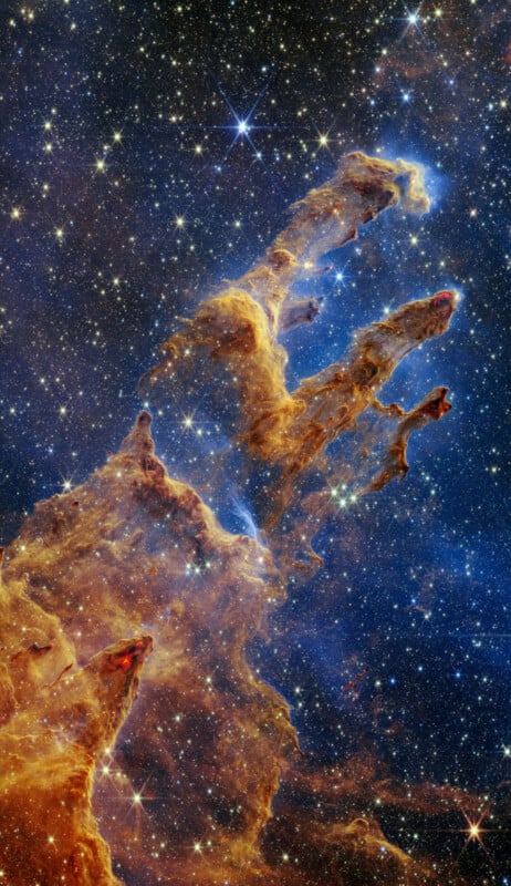 A vibrant image of the Pillars of Creation in the Eagle Nebula, captured by the James Webb Space Telescope. The towering columns of semi-transparent gas and dust are surrounded by a starry background, featuring a mix of deep blues, reds and golden hues.