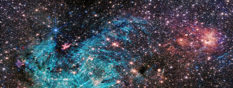 Image of a galaxy filled with stars and dense star clusters. A prominent blue nebula appears at center left, with complex shapes and streaks. To the right, there is a red-orange area with a cloudy, fiery appearance. The background is black like deep space.