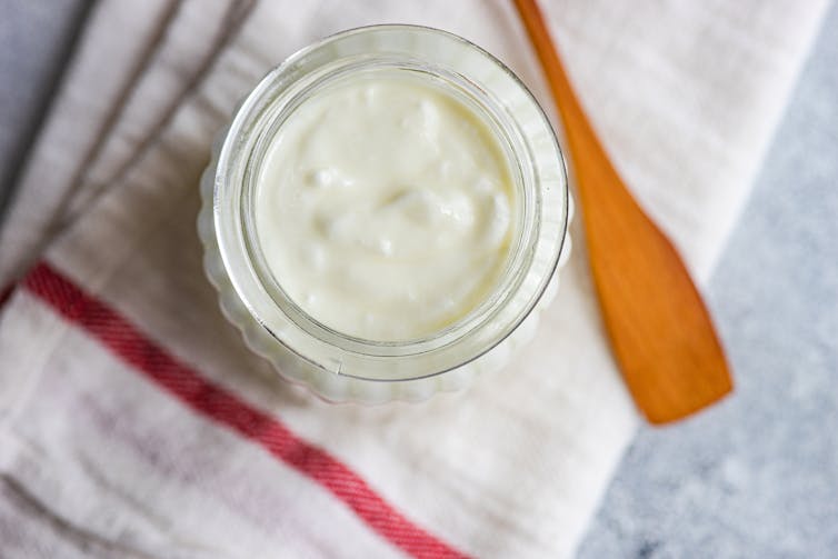 Yogurt pot and wooden spoon on a napkin