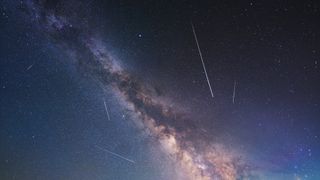 Meteor shower trails appear as long streaks of white light against the backdrop of the Milky Way.