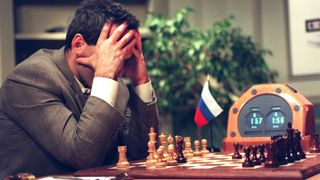 Garry Kasparov holds his head in his hands as he sits in front of a chessboard