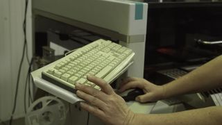 A hand rests on an old computer keyboard