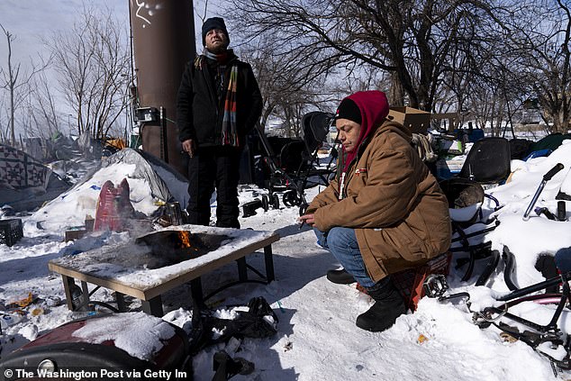 However, fewer and fewer affordable housing units are being built, meaning rising prices have pushed many people onto the streets. Cyrus Whittaker, left, and Debbie Orca sit around a fire in the homeless camp where they live during record cold and snow in Oklahoma City, Feb. 16, 2021